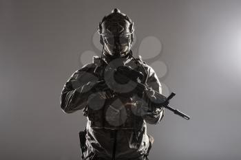 Army soldier in Protective Combat Uniform holding Special Operations Forces Combat Assault Rifle. Studio shot, low key, cropped, black dark background, contour shot
