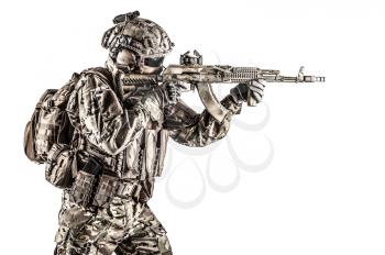 Operator of Russian special operations forces with kalashnikov assault rifle, military backpack and combat helmet shooting a weapon. Studio shot, isolated on white background, profile view