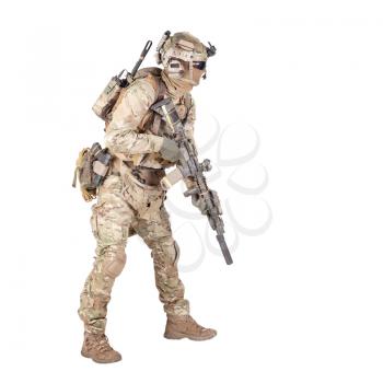 Modern army infantry rifleman in camo uniform, radio headset on helmet, ammo on load carrier, sneaking, crouching, aiming and shooting with service rifle studio shoot isolated on white background