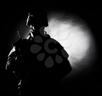 Silhouette photo of army soldier, modern combatant, military conflict participant standing in combat uniform with fiery spot on black background. Fire of war, ashes of battle, nuclear fire concept