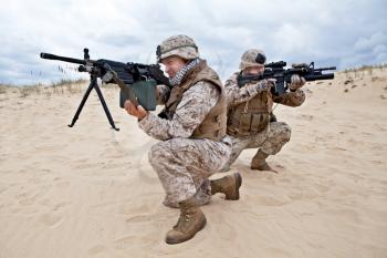 two US marines aim at different directions covering each other