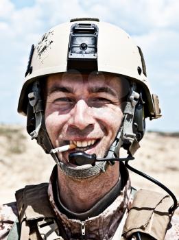 smiling US soldier in the desert smoking a cigarette