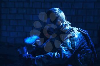 Special forces soldier after the fight sitting in ruined building smoking cigarette staring at the camera
