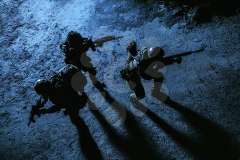 Black silhouette of soldiers at night. View from above, toned and colorized. Squad in action