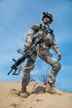 United states airborne infantry man with arms, camo uniforms dress. Combat helmet, knee pads protection wearing, low angle view from below, full body