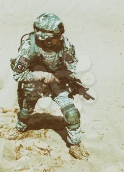 United states airborne infantry man with arms, camo uniforms dress. Combat helmet, knee pads protection wearing, moving desert high angle top view