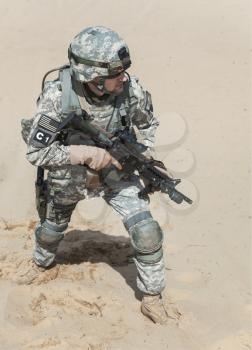 United states airborne infantry man with arms, camo uniforms dress. Combat helmet, knee pads protection wearing, moving desert high angle top view