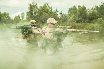 Navy SEALs crossing the river with weapons 