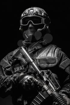 Spec ops police officer SWAT in black uniform and face mask studio shot