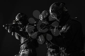 Spec ops police officers SWAT in black uniform and face mask studio shot
