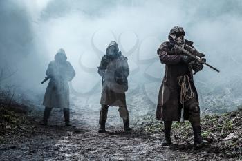 Nuclear post-apocalypse. Survivors in tatters and gas mask on the ruins of the destroyed city