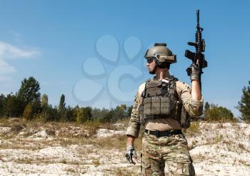 US Army Ranger with weapons in the desert. Plate carrier, eyewear goggles and combat helmet are protecting him