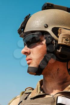 US Army Ranger with weapons in the desert beneath a scorching sun. Closeup face portrait. He is wearing eyewear goggles protection and combat helmet