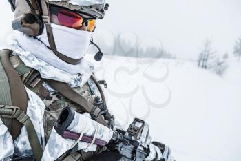 Winter arctic mountains warfare. Action in cold conditions. Trooper with weapons in forest somewhere above the Arctic Circle