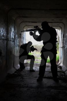 Silhouette of special forces operators with weapons in the tunnel