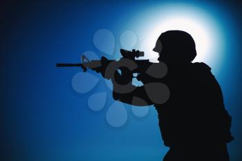 Modern army infantry soldier, coast guard rifleman aiming assault rifle with collimator sight at night. Special operations forces fighter engaging enemy in darkness, observing territory during mission