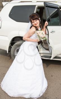 Bride with bouquet at the open car door