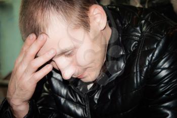 Portrait of the thoughtful young man with a hand at a forehead