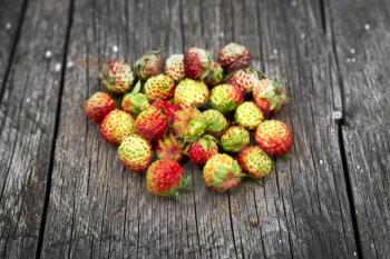 Bunch of red wild strawberry on the old wooden background