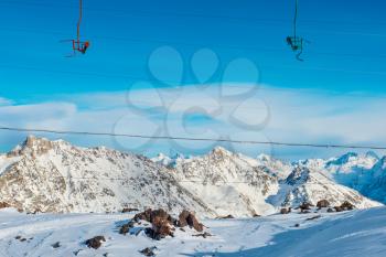 Cableway in snowy blue mountains with clouds. Winter ski resort