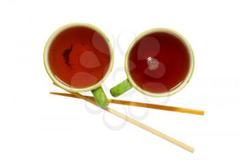 Two teacups with tea and chopsticks isolated on white.