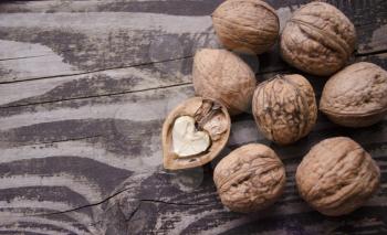 Walnuts on a grey textured wooden table. Assortment of nuts isolated on rustic old wooden background and splintered walnut with heart-shaped core. Walnuts close up.