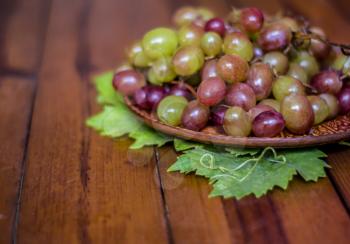 Grapes on a clay plate on a wooden tables .Still life with pink muscat grapes.