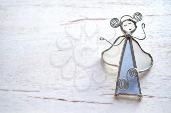 Angel figurine of the glass and wire isolated on wooden background. Abstraction