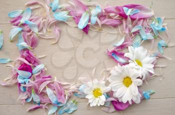 Top view of floral wreath frame with blue and pink petals isolated on wooden background with free space for text.