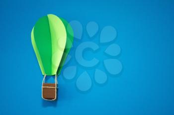 Handmade green hot air balloon in the sky. Paper art style. Isolates on blue background. Blank for motivating quote, note, message and comment. Idea for poster, banner, flyer.