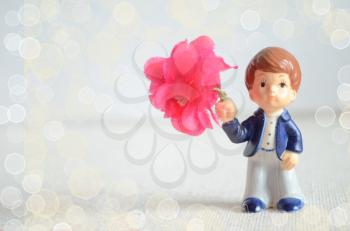 Valentine greeting card with romantic boy figurine with bouquet of flowers.