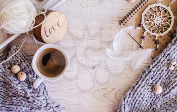 Cozy composition with coffee, knitted elements from merino wool on a wooden background. A photo in a Hygge style.