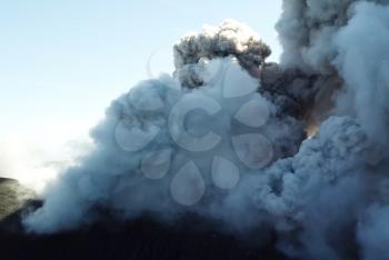 Smoke from the mouth of the volcano. Eruption. Clubs of smoke and ash in the atmosphere.