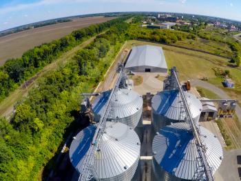 Flight of the grain terminal from the drone. The grain plant for storage and drying of grain. Grain terminal. Plant for the drying and storage Rice plant in the middle of fields.