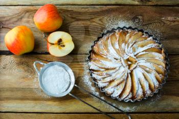 Apple pie, dessert tart with fresh fruits and caster sugar on wooden table, top view
