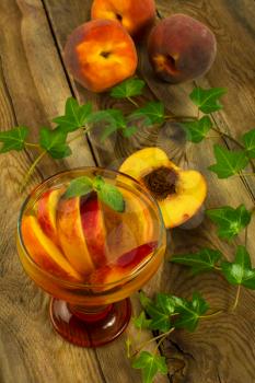 Cold drink, iced green tea with peaches and mint in a glass on a dark wooden background, vertical, top view, selective focus