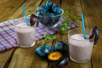 Fruit drink, plum smoothies, prune yogurt, diet healthy drink in a glass on a dark wooden background, horizontal. Selective focus