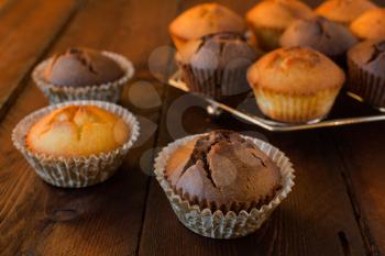 Vanilla and chocolate muffins on a dark wooden background, selective focus
