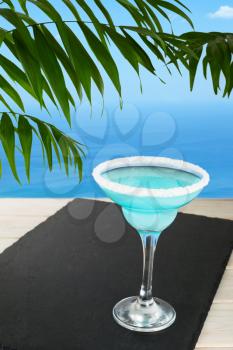Blue cocktail on the tropical beach. Blue Lagoon margarita martini cocktail. Summer beach alcohol drink.  Iced blue cosmopolitan cocktail.