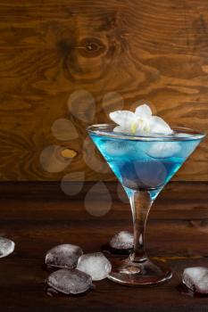 Blue cosmopolitan cocktail on wooden background. Blue margarita. Blue cosmopolitan. Blue Lagoon. Blue cocktail. Blue Martini. Blue Hawaiian cocktail. Blue curacao liqueur. 