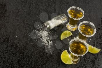 Gold tequila with lime on black background, top view. Tequila shot. Tequila. Gold Mexican tequila