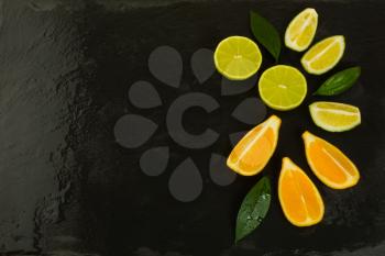 Lime and Lemon slices on black background. Healthy eating concept with ripe mixed fruits. Vegan and vegetarian food as fruit background. 