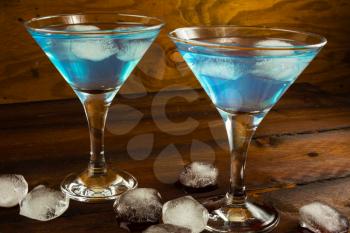 Two blue cocktails in glasses on dark wooden background. Blue Martini. Blue Hawaiian cocktail