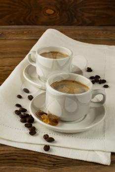 Two coffee cups and brown sugar on the linen napkin, vertical. Coffee break for two persons