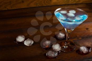 Iced blue cosmopolitan cocktail on wooden background. Blue margarita. Blue cosmopolitan. Blue Lagoon. Blue cocktail. Blue Martini. Blue Hawaiian cocktail. Blue curacao liqueur.