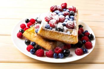 Belgian waffles with blueberry and raspberry powdered by caster sugar. Breakfast soft waffles with fresh berries. 