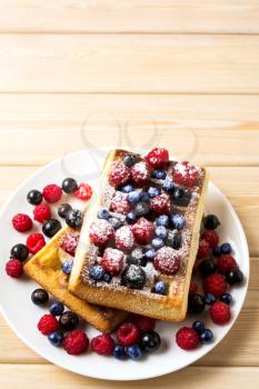 Soft Belgian waffles with blueberry, raspberry, blackcurrant and caster sugar copy space. Breakfast waffles with fresh berries.