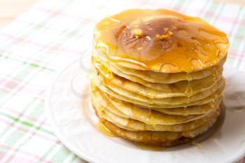 Stack of breakfast pancakes with honey on the white plate. Homemade pancakes served for breakfast.