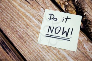 Do it now conceptual handwritten message on the white paper. Business concept handwritten messages. Motivational and positive handwritten message with wooden background.
