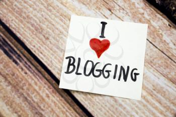 I love blogging message with red heart symbol on the white paper with retro wooden background. Online bloggers conceptual message on the white paper. Internet business concepts.